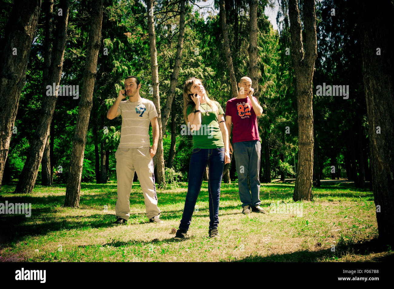 Three teenagers talking to the phone in the forest Stock Photo