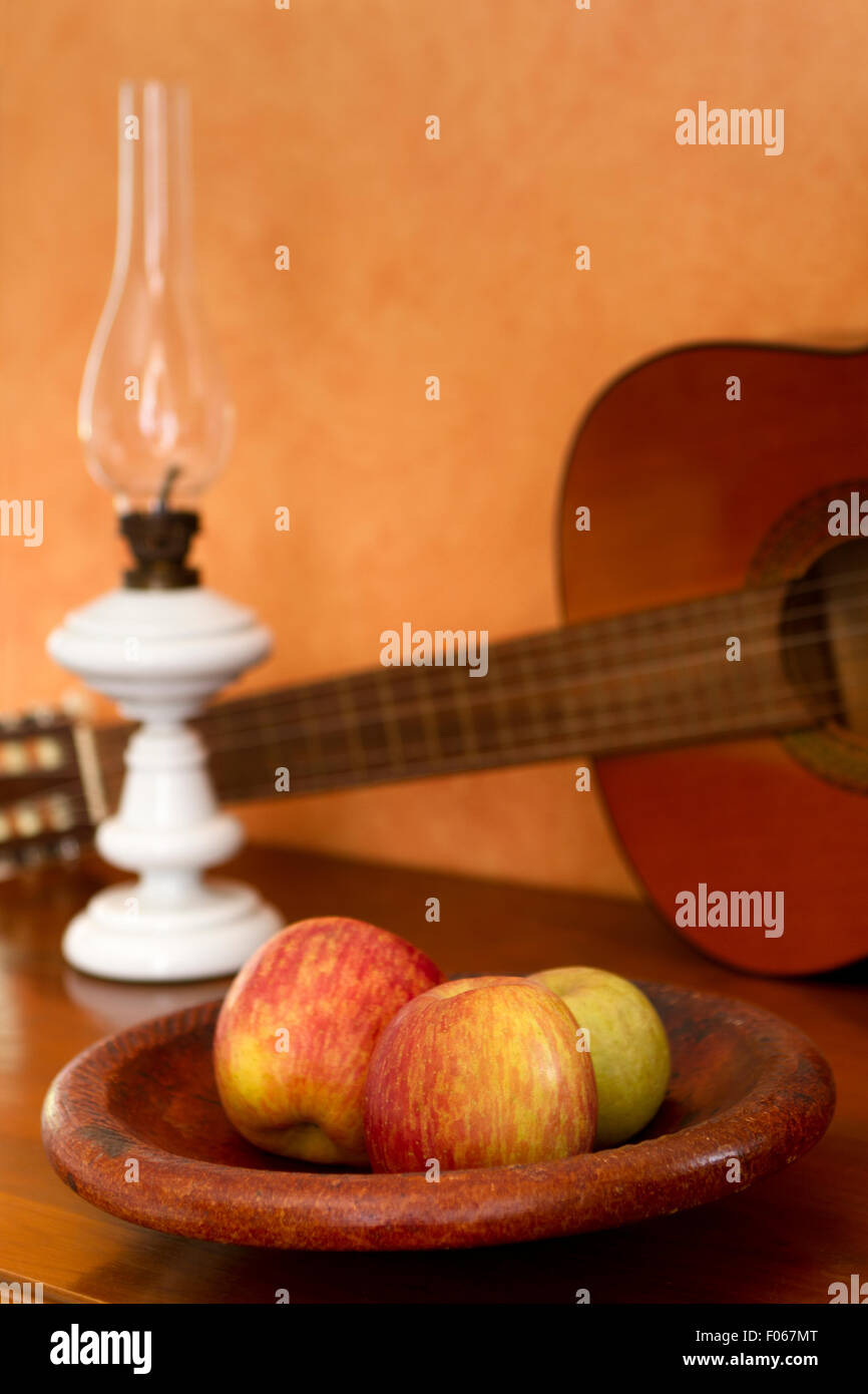 Latin American still life with guitar apples and lamp Stock Photo