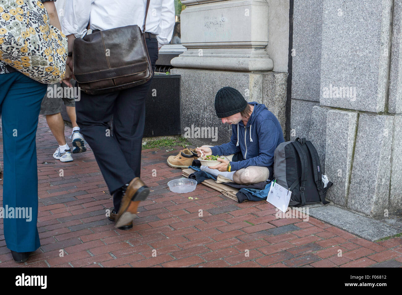 Homeless person eating on the sidewalk in Cambridge, MA Stock Photo