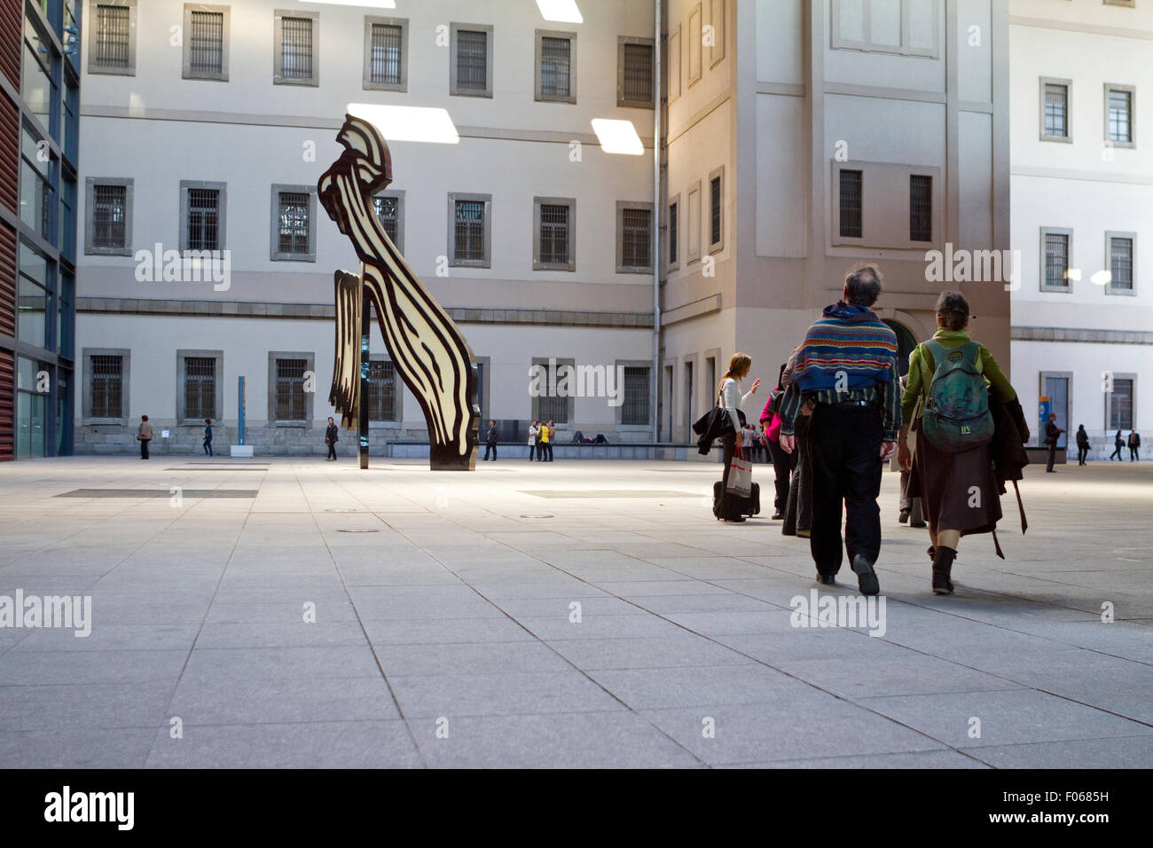 Visitors walking near the Brushstroke sculpture by Roy Lichtenstein in the court of Reina Sofia Museum in Madrid (Spain). Stock Photo