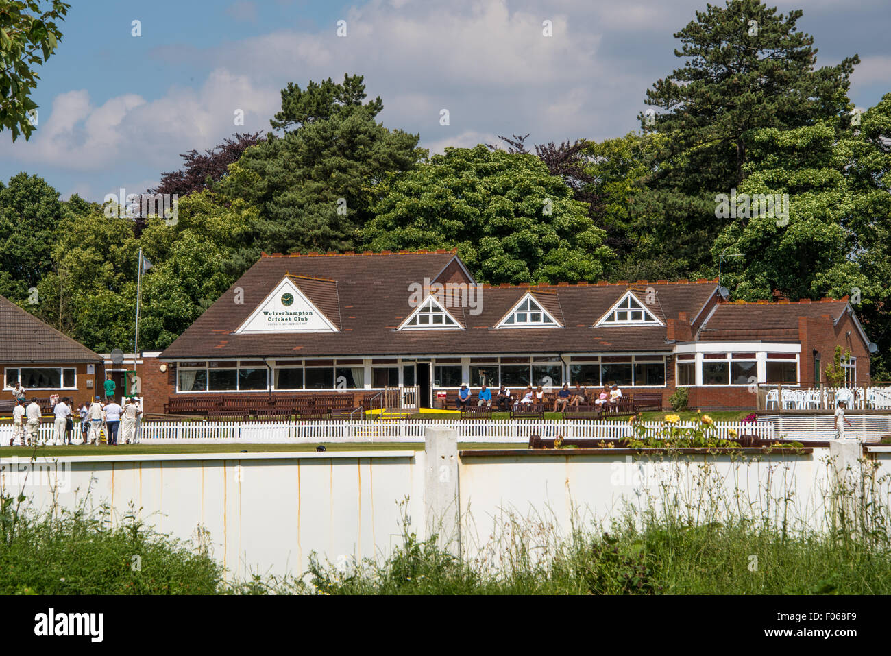Wolverhampton Cricket club Pavilion  with people sat outside and the Cricket team on the pitch in Wolverhampton West midlands UK Stock Photo