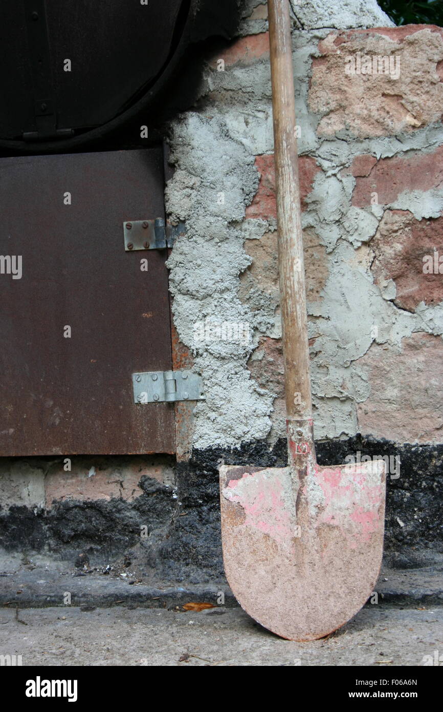 Rusted shovel by a stone wall. Stock Photo