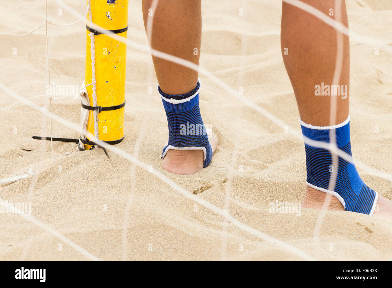 Footballer wearing ankle protectors while playing beach football Stock
