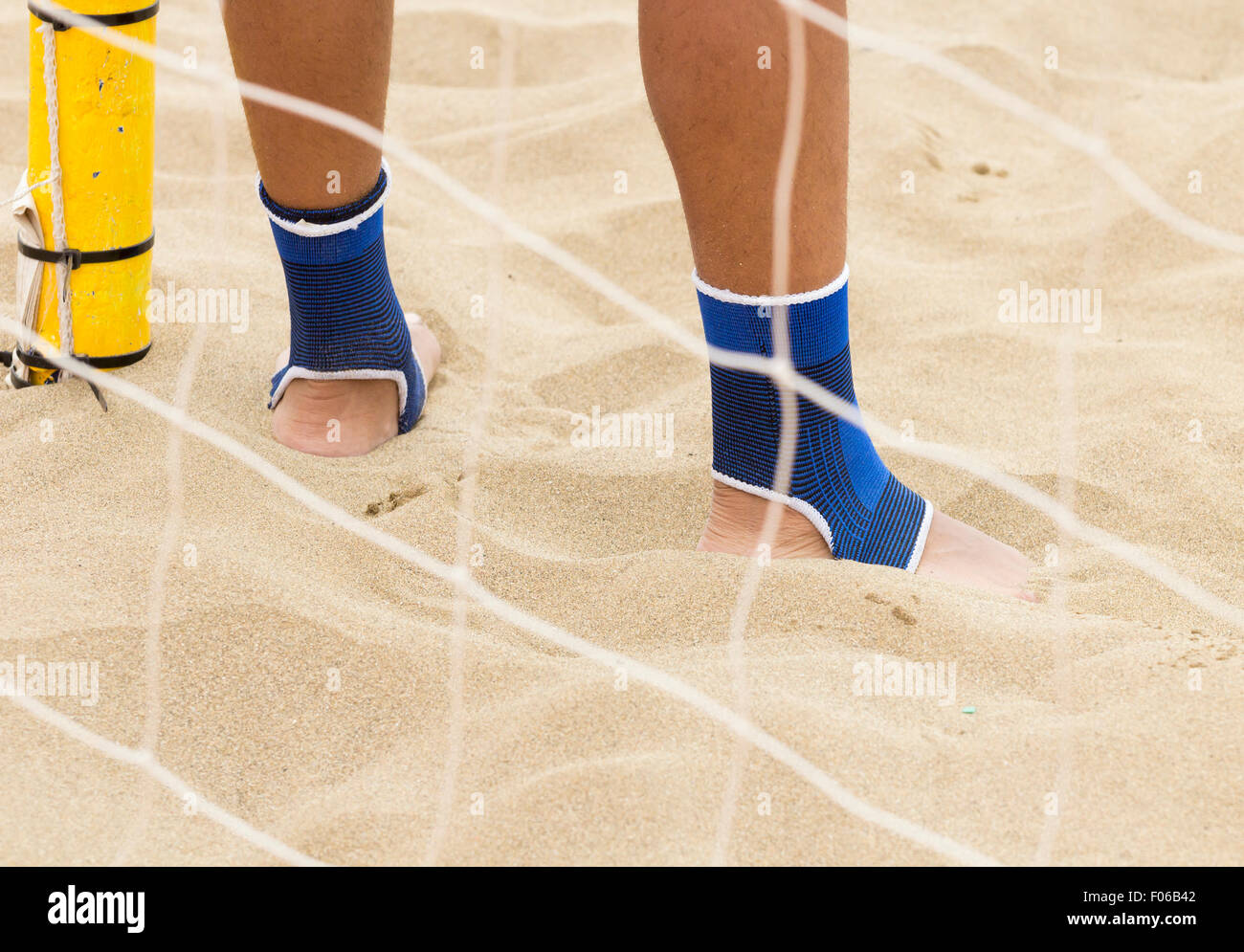 Footballer wearing ankle protectors while playing beach football Stock