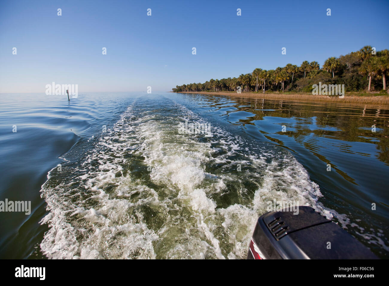 Boat wake churning up very calm water with pleasing reflections and leading lines Stock Photo