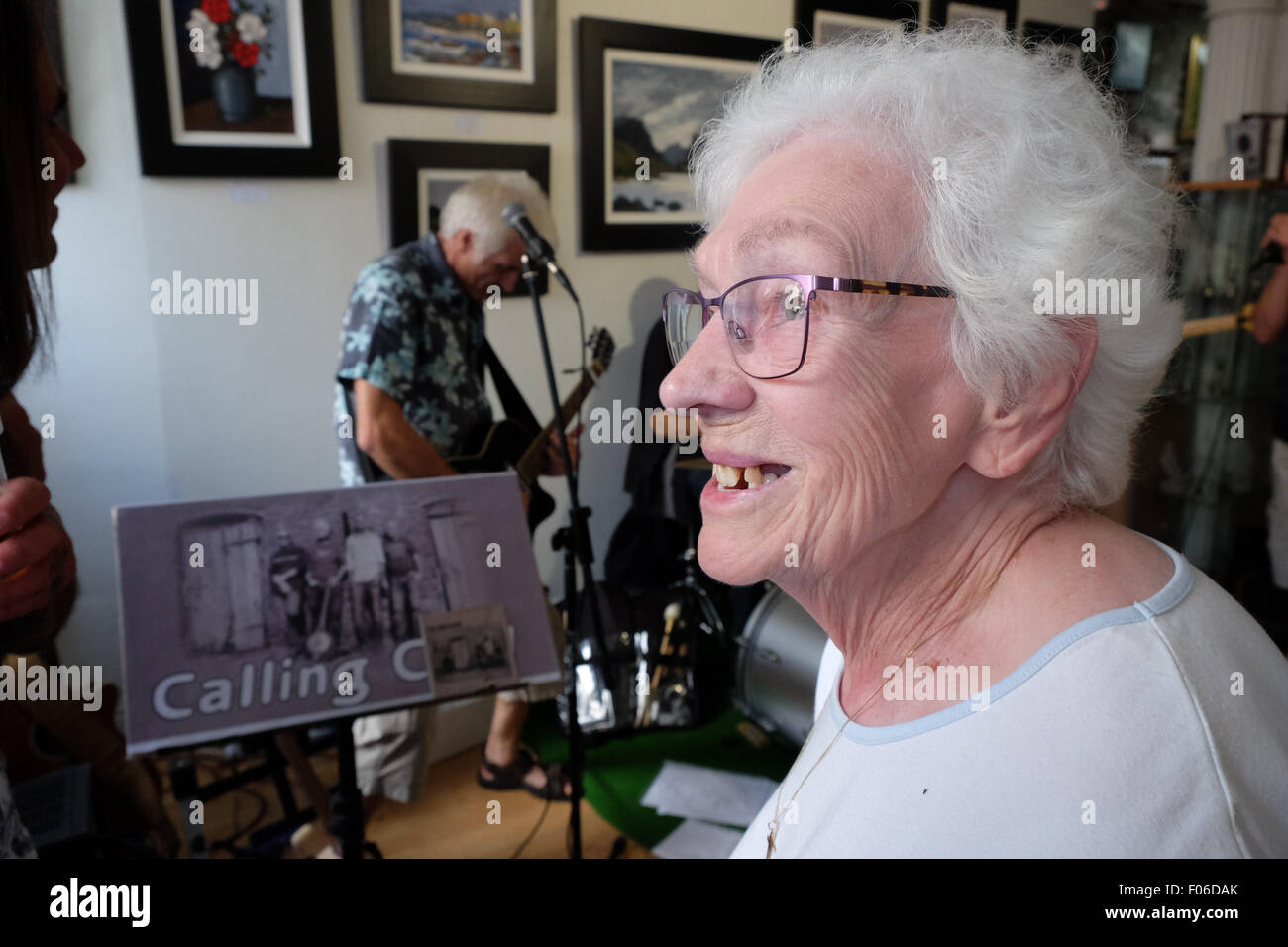 Brecon, Powys, Wales, UK. 8th Aug, 2015. An elderly woman enjoys the live music among the art inside the Ardent Gallery in Brecon town centre one of many live music venues during the Brecon Festival weekend. Stock Photo