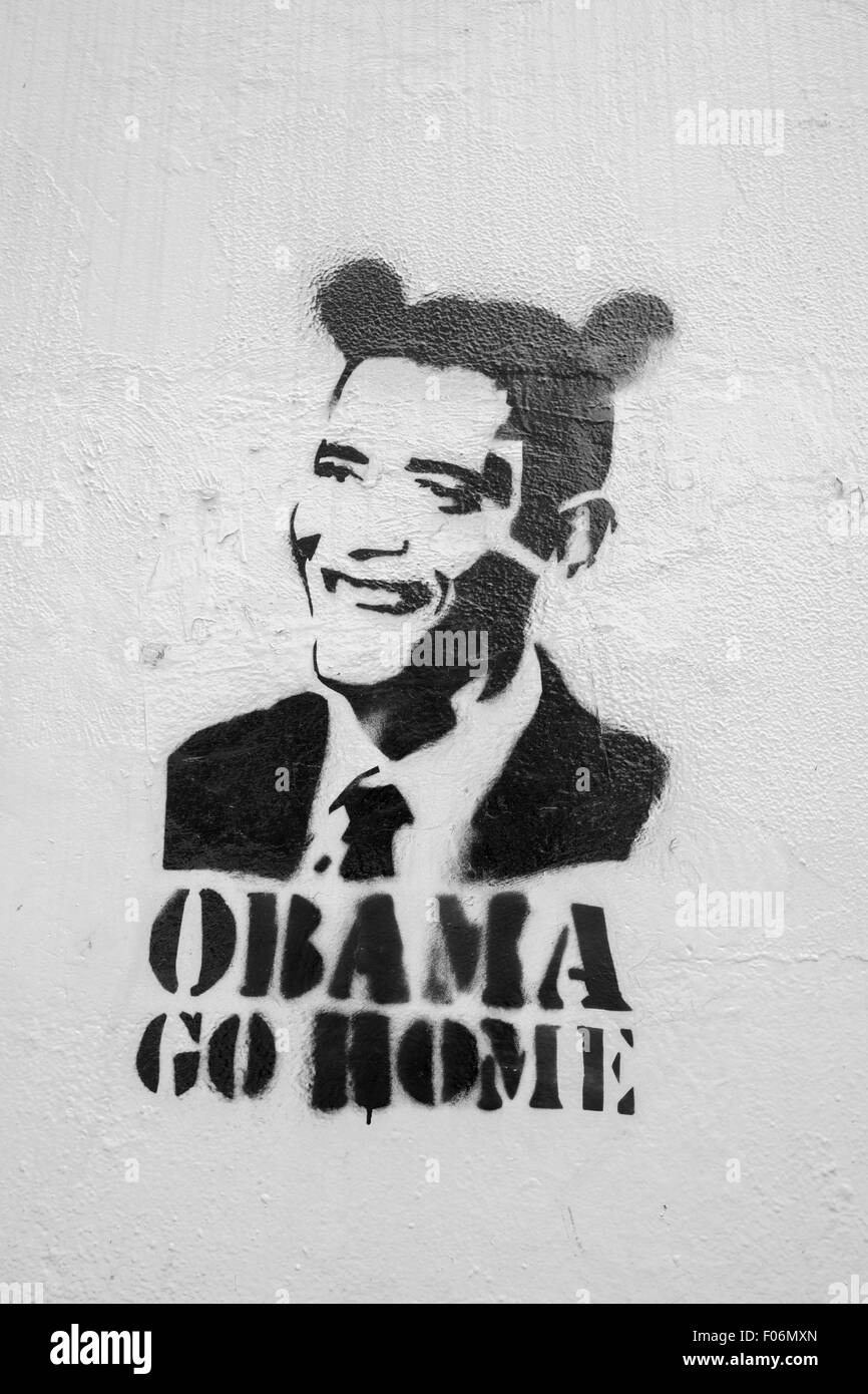 Black Graffiti on white wall with President Obama in Disney style and words saying Obama go home. Political message in downtown Stock Photo
