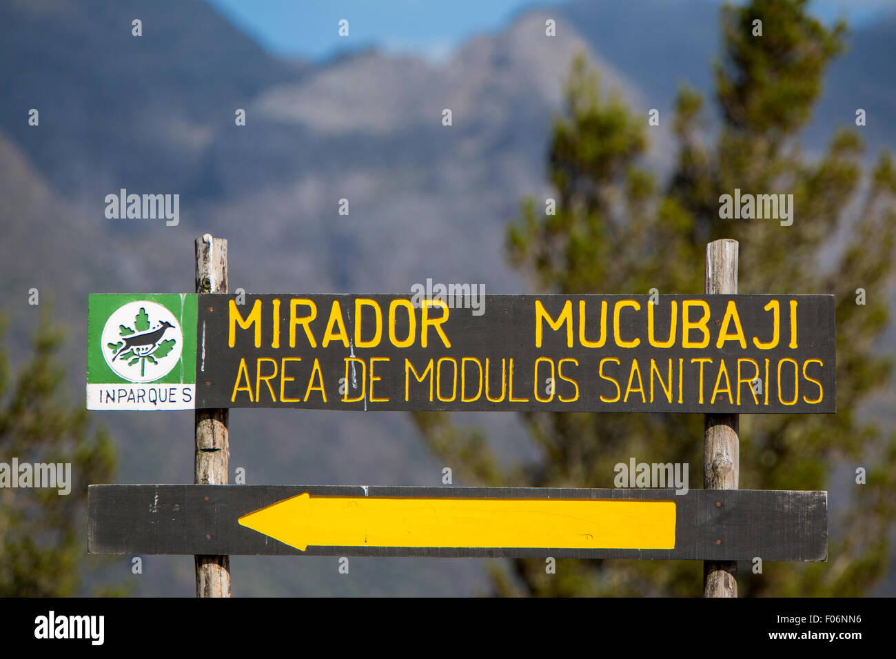 Wooden road sign showing the direction toward the Mirador Mucubaji with the forest and mountains in the background. Stock Photo