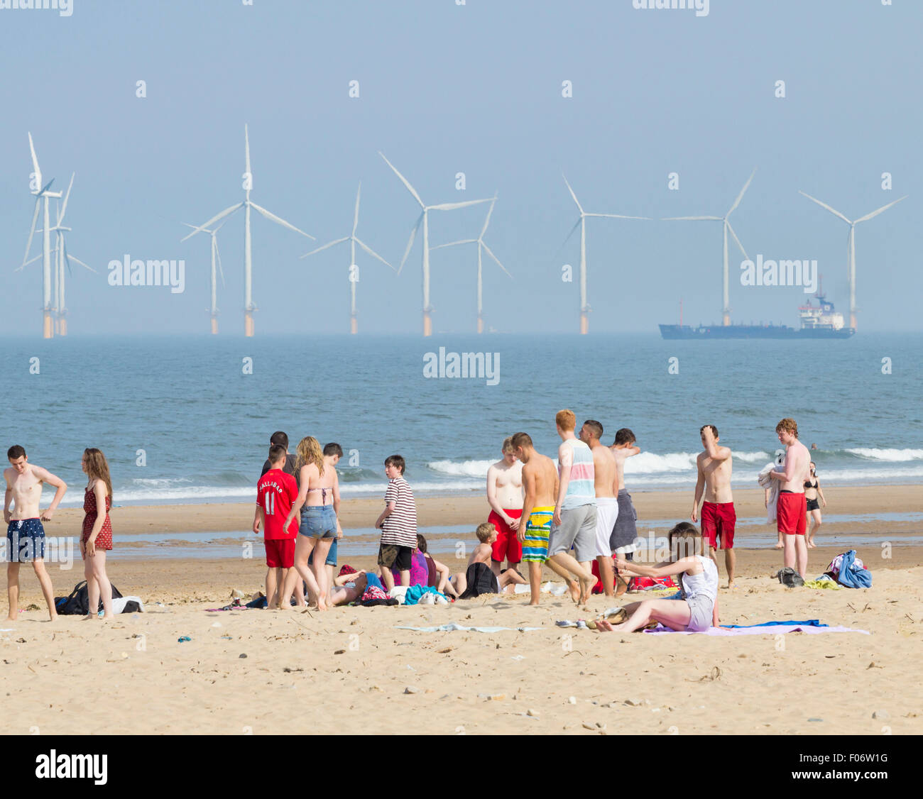 Teenagers on Seaton Carew beach with Teesside Offshore Wind Farm in background. Seaton Carew, north east England. UK Stock Photo