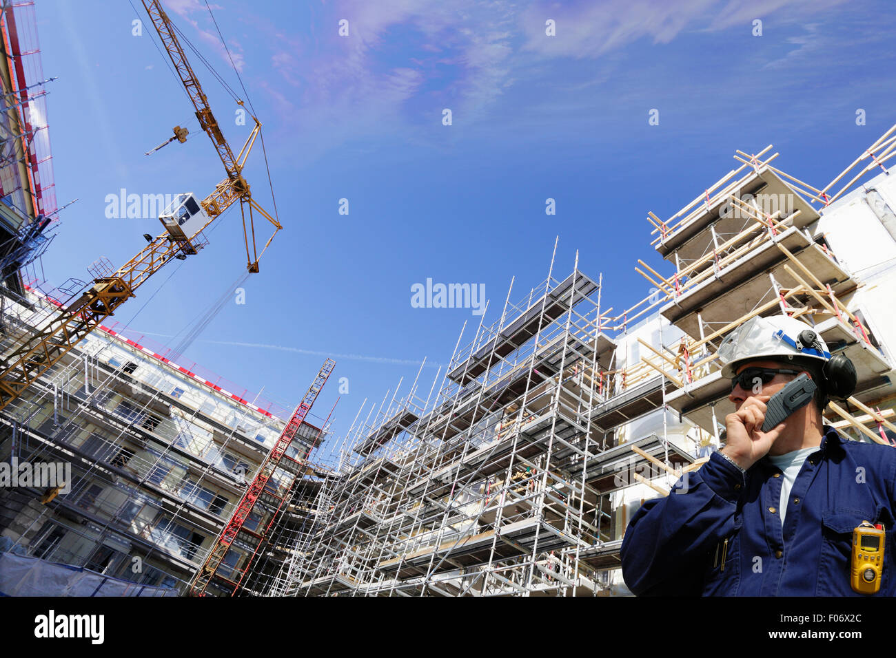 building worker inside construction site, cranes and scaffolding Stock Photo