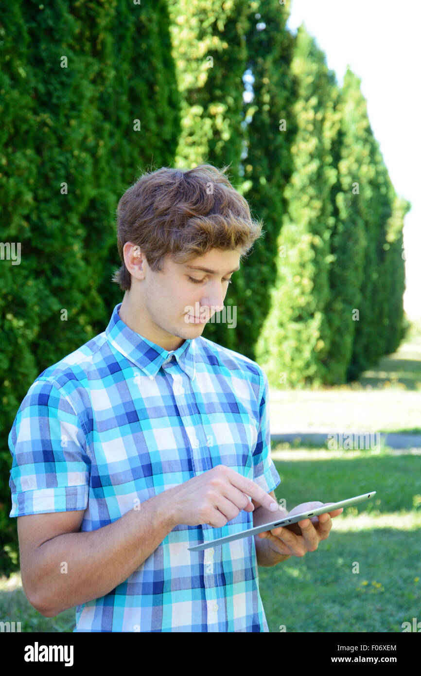 Young Man Using Tablet Young man is using tablet in the park Stock Photo - Alamy