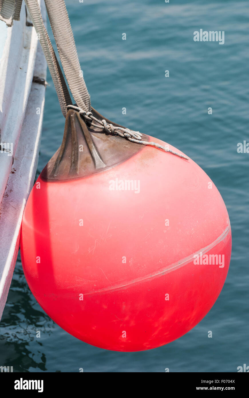 Red buoy hanging on the aboard of fishing boat. Closeup Stock Photo