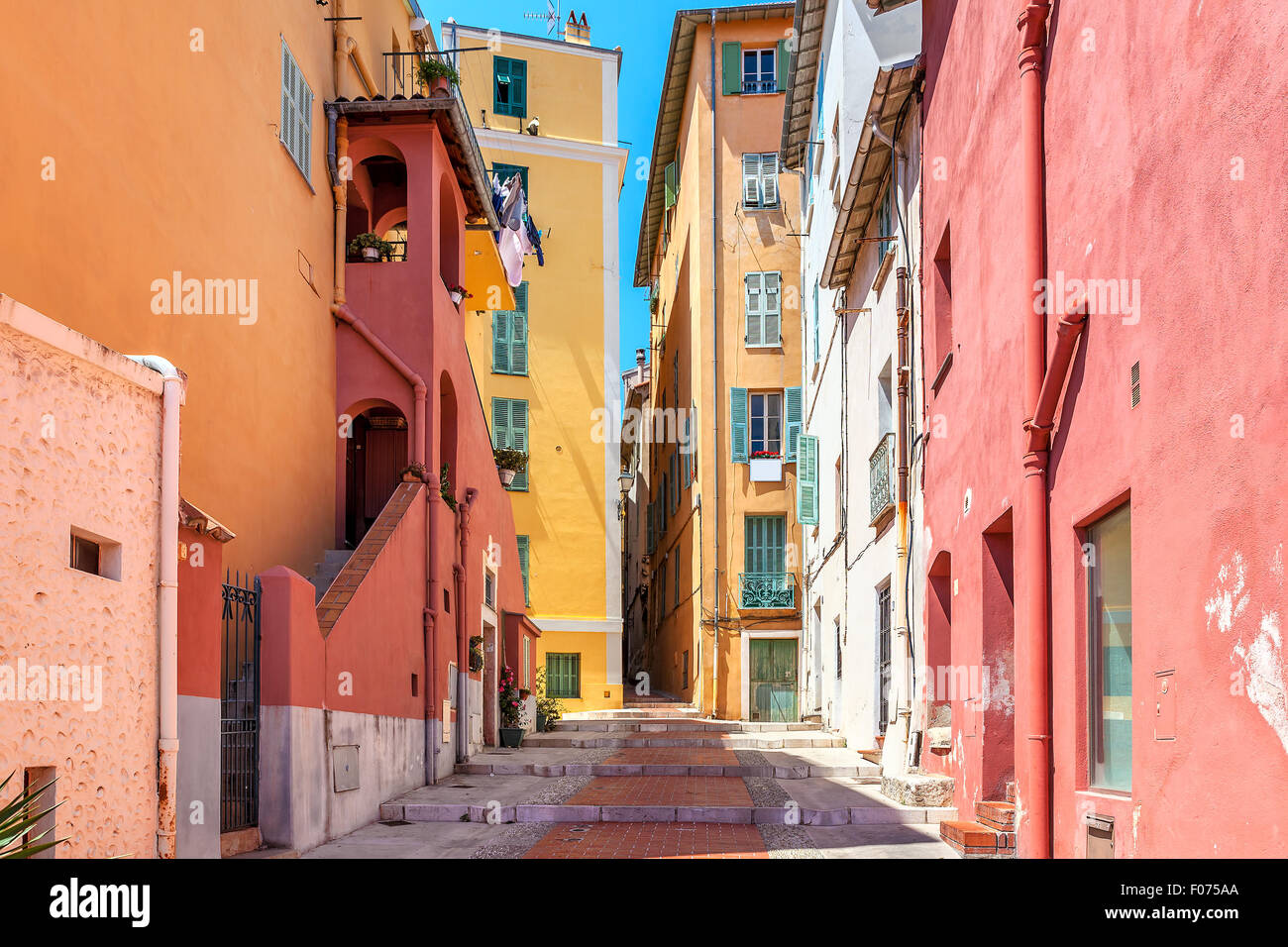 Narrow street among old colorful houses in Menton, France. Stock Photo