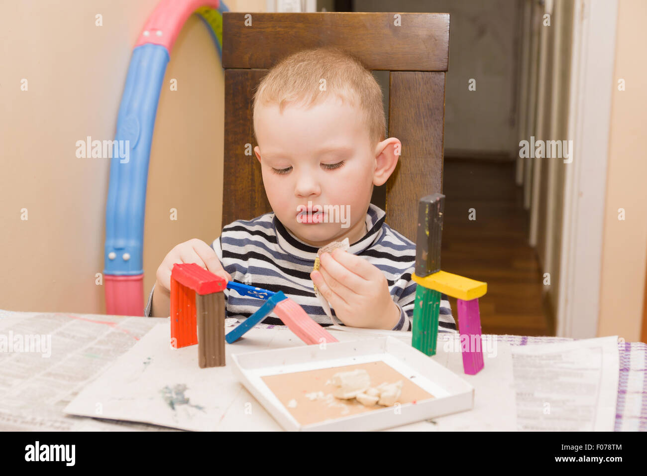 the little boy sits at a table and is engaged in a molding from plasticine Stock Photo