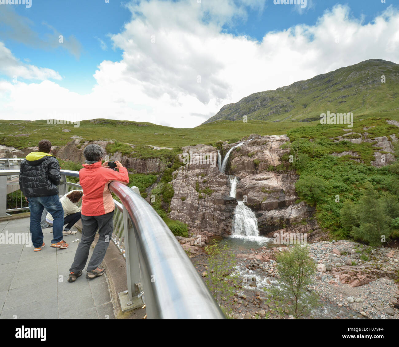 Allt Lairig Eide waterfall - tourists taking photographs - from the viewpoint on the A82 road through Glencoe, Scotland, UK Stock Photo