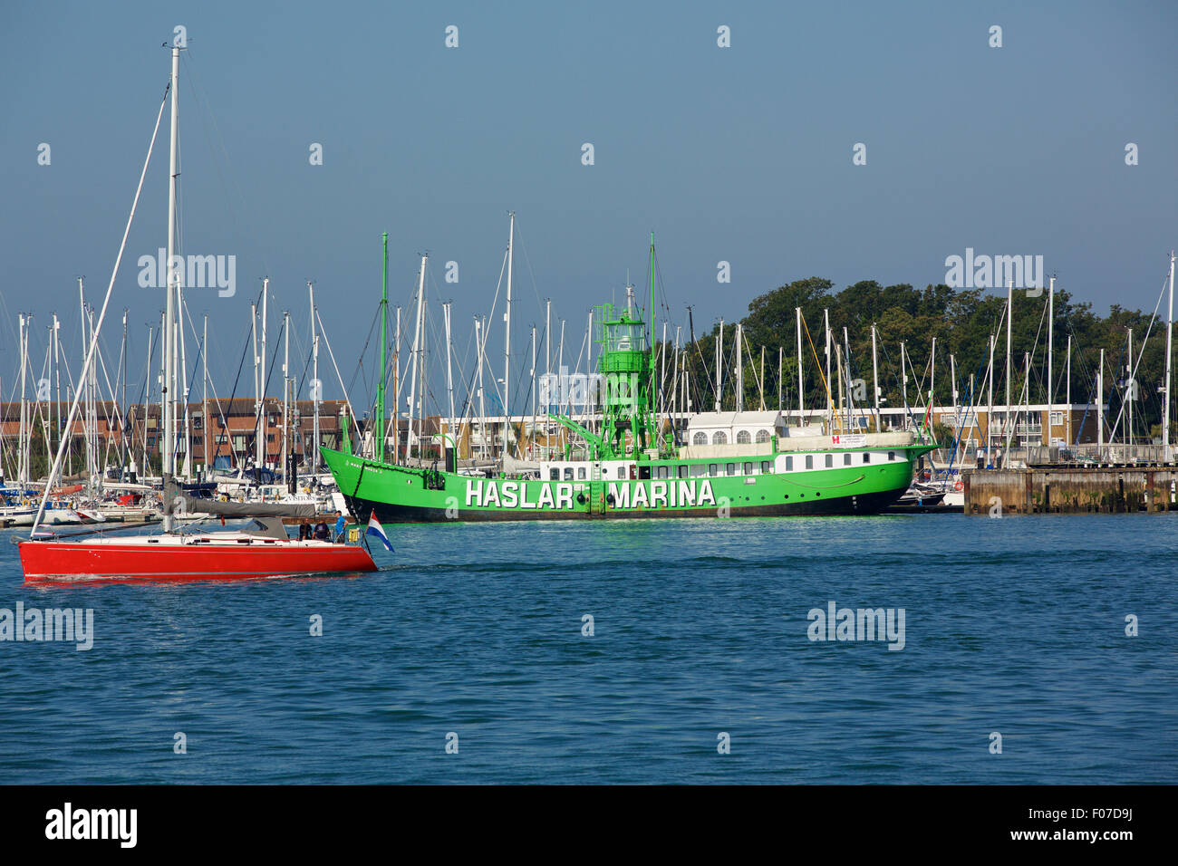 Renovated light ship moored in Haslar Marina Gosport. Many moored yachts behind and a yacht underway in the foreground. Stock Photo