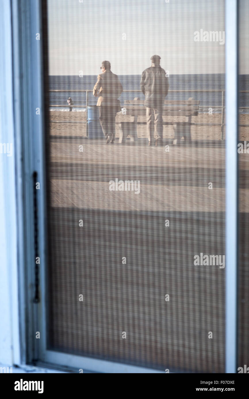 Boardwalk, ocean, and beach-goers reflected in storefront window. Asbury Park, New Jersey Stock Photo