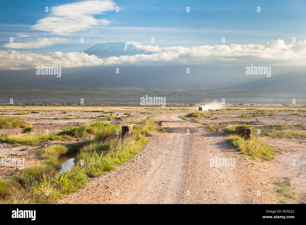 Kilimanjaro with snow cap seen from Amboseli National Park in Kenya with a road in the foreground. Stock Photo