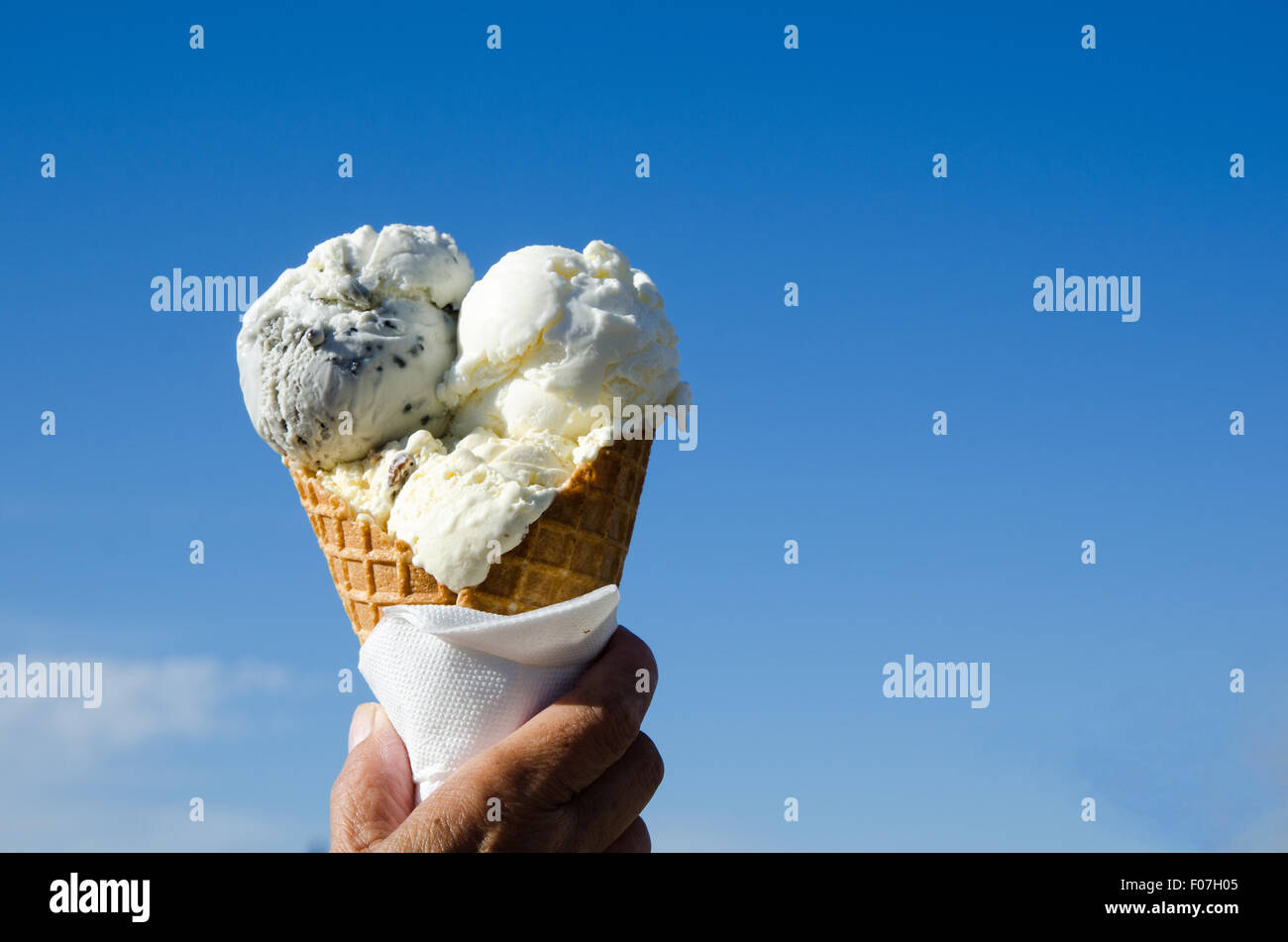 Hand is holding an ice cream cone at a blue sky Stock Photo