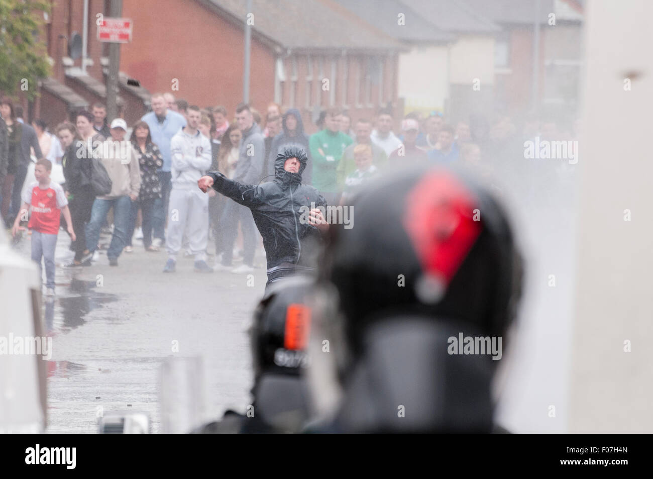 Belfast, Northern Ireland. 09 Aug 2015 - A nationalist youth throws a stone at PSNI officers while being sprayed by a water cannon following an anti-internment rally. Credit:  Stephen Barnes/Alamy Live News Stock Photo