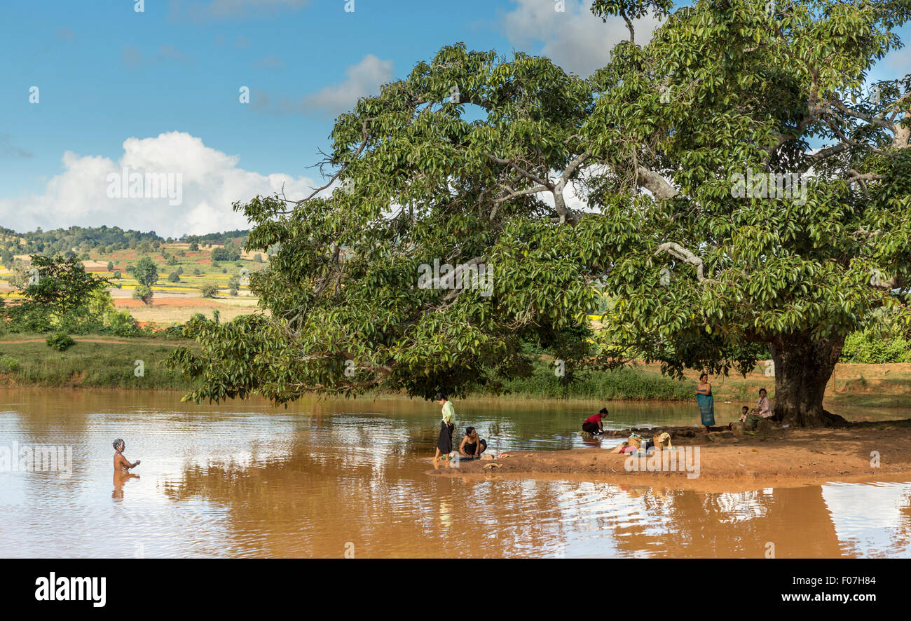 Women bathing and washing clothes in a muddy lake along the main road