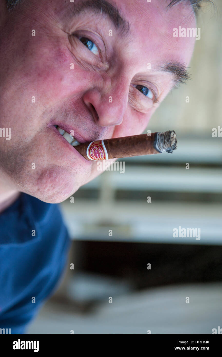 A man enjoys a cigar and makes funny faces whilst smoking Stock Photo -  Alamy