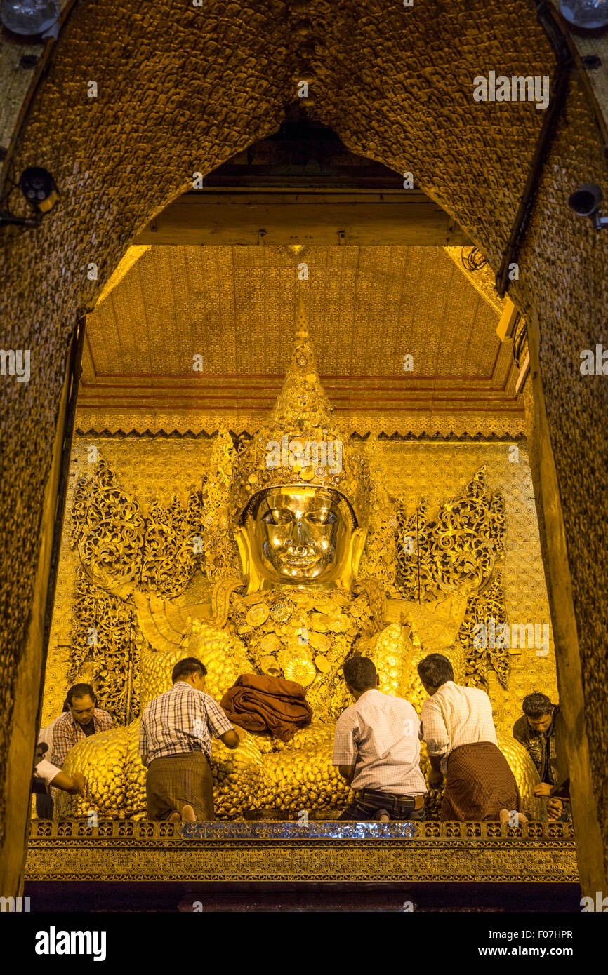 Workers apply gold leaf to Buddha statue at Mahamuni Pagoda, Yangon