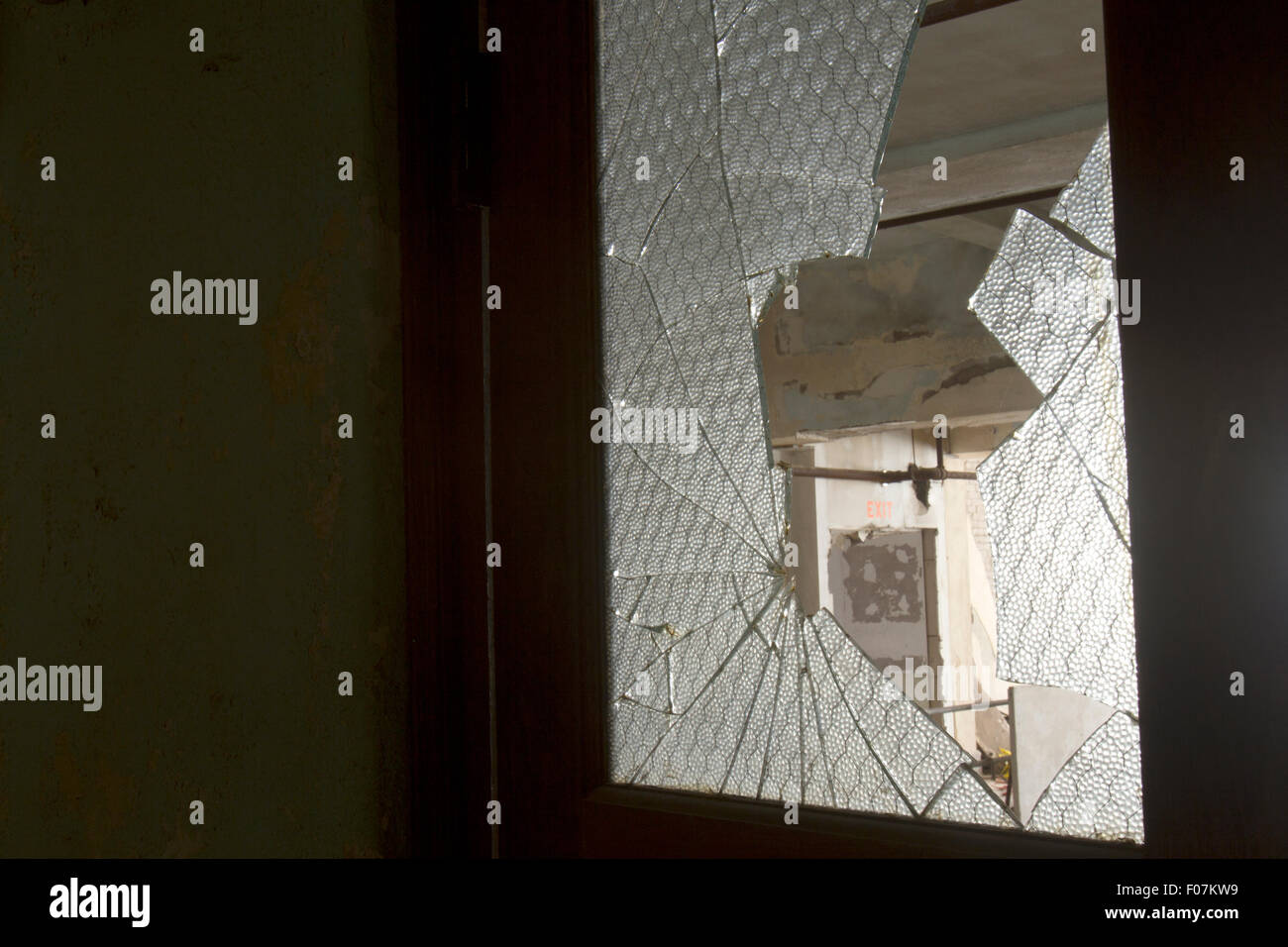 Broken glass in door with exit sign in frame. Stock Photo