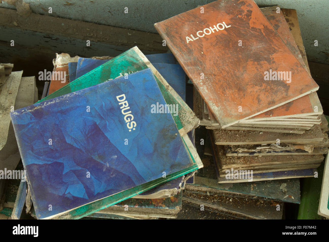 Rotting primers on drugs and alcohol on top of old school books. Stock Photo