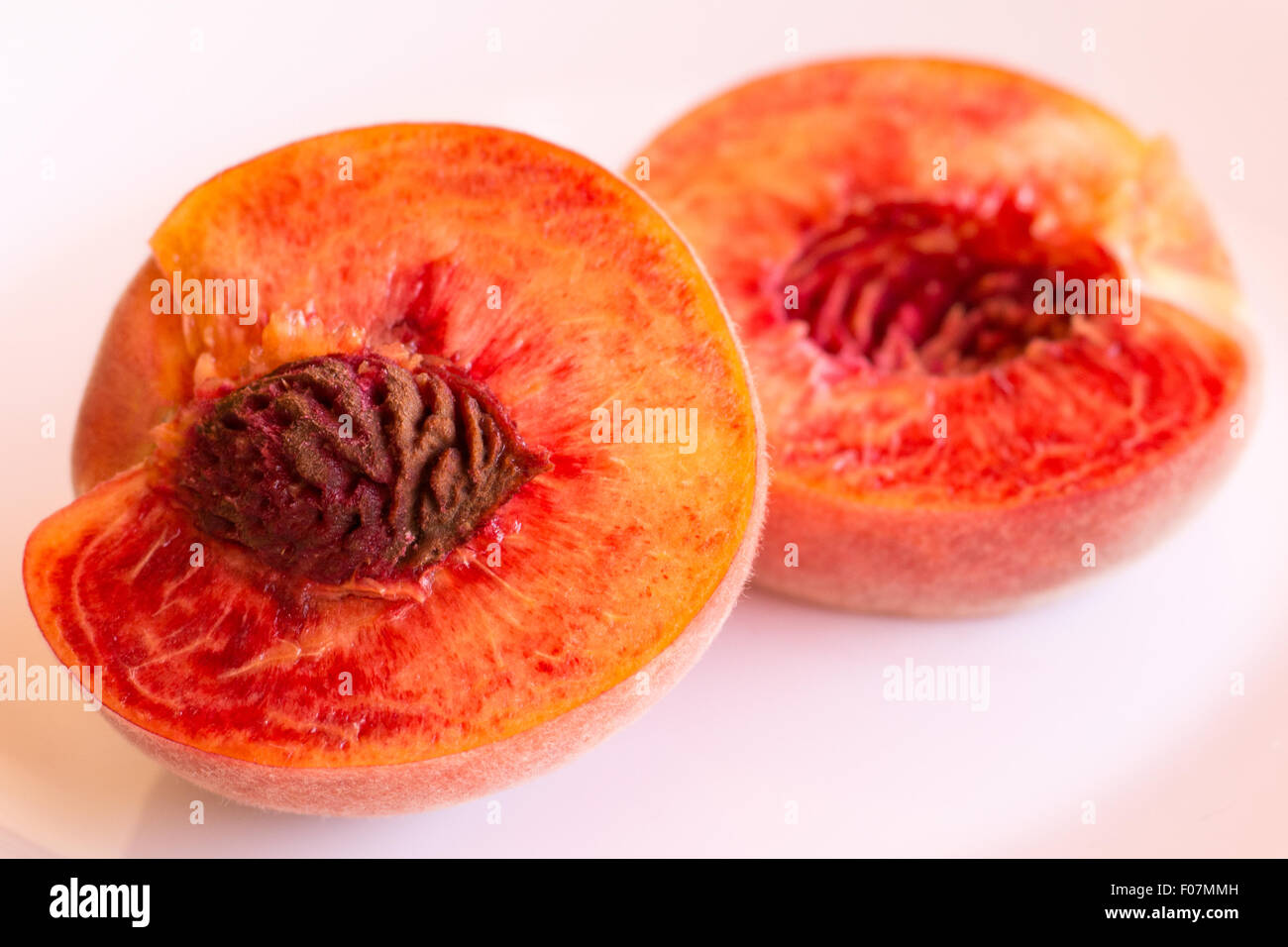 One mature peach, cut in half, on a white background Stock Photo Alamy