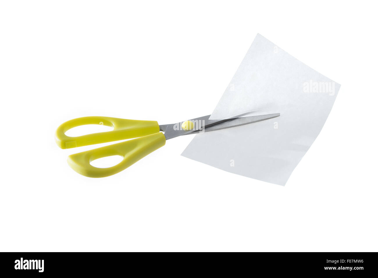 A pair of yellow scissors cutting a piece of white paper isolated on a white background. Stock Photo