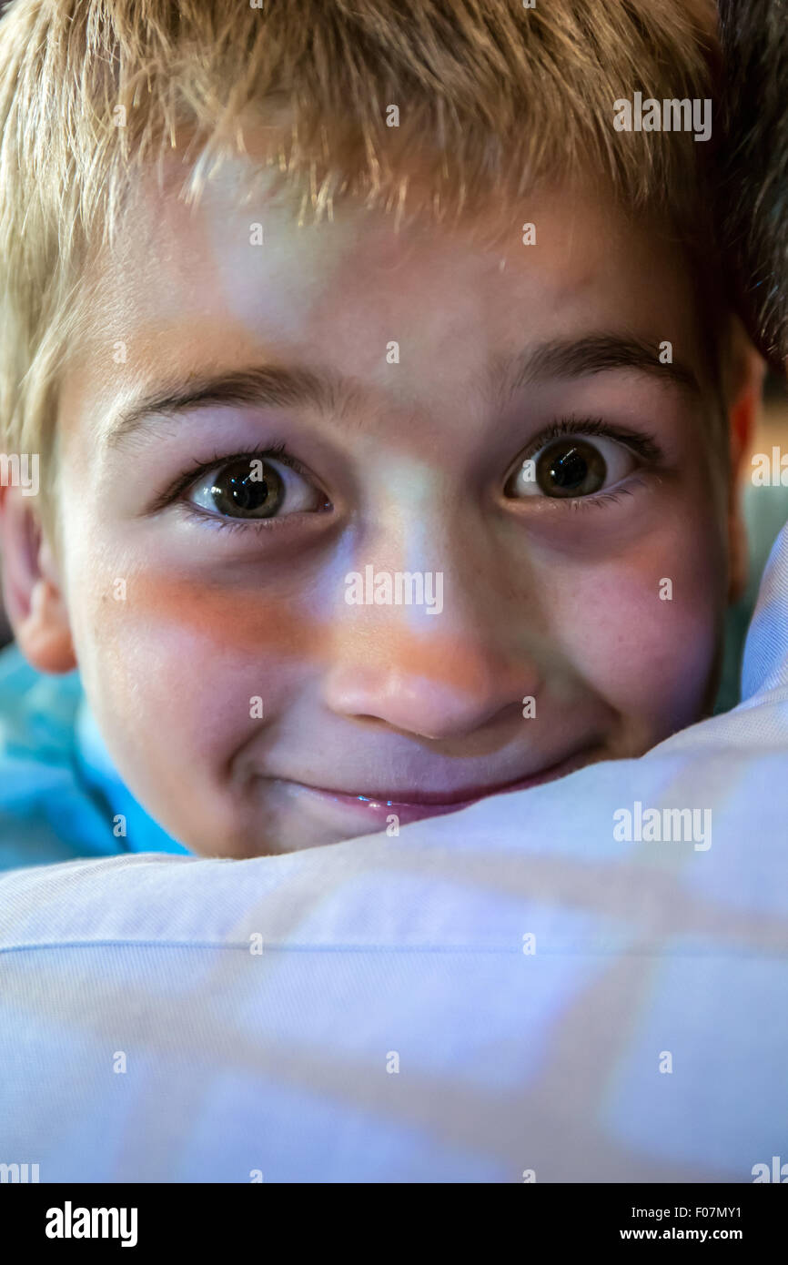 Seven year old boy peeking over the shoulder of his grandfather, with a window reflection on them, in Seattle, Washington, USA Stock Photo