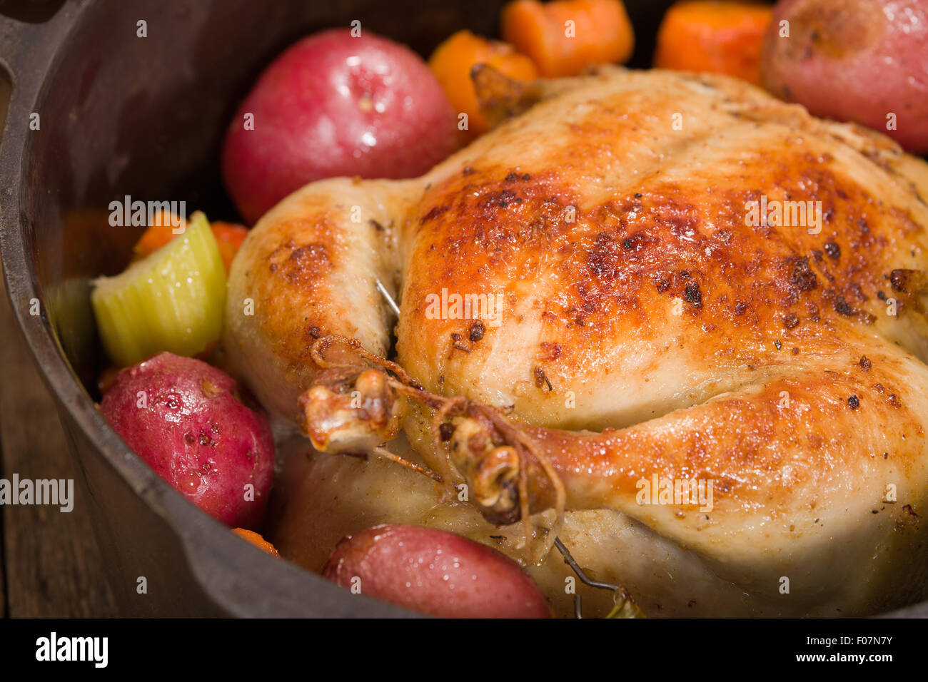 Dutch-style roasted chicken with baked red potatoes, carrots and celery, in a cast iron pot Stock Photo