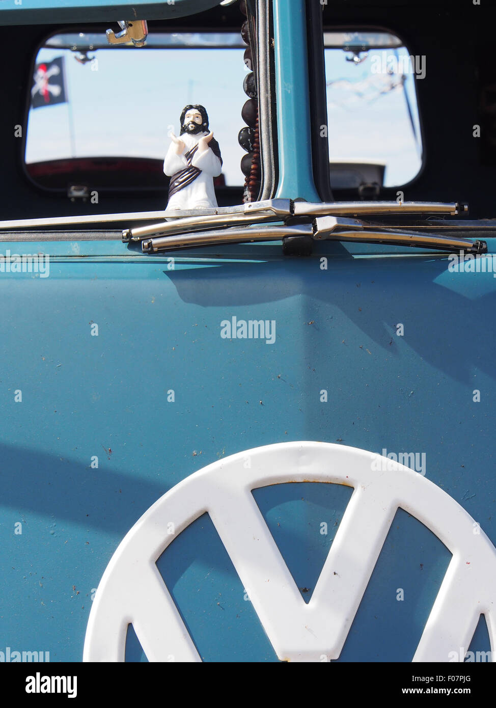 A buddy Christ figurine in the window of a VW camper van Stock Photo