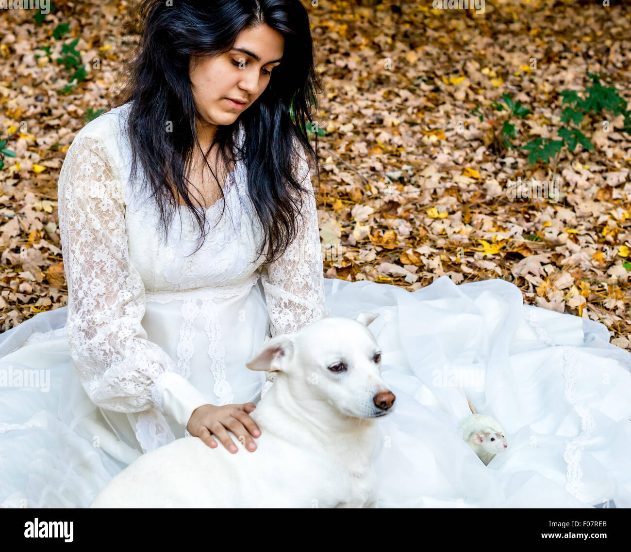 Latina teenage girl sitting outside in the autumn leaves with her pet dog and rat Stock Photo