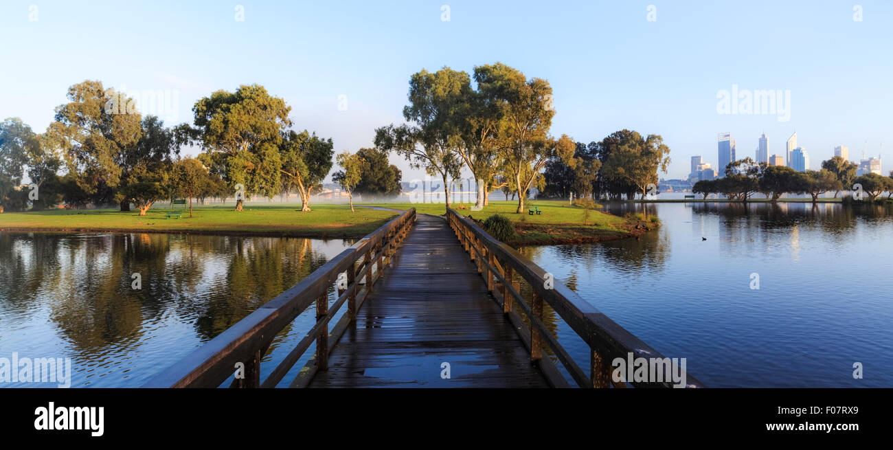 A footbridge over a lake in Sir James Mitchell Park, South Perth, with Perth city in the distance. Western Australia, Australia. Stock Photo