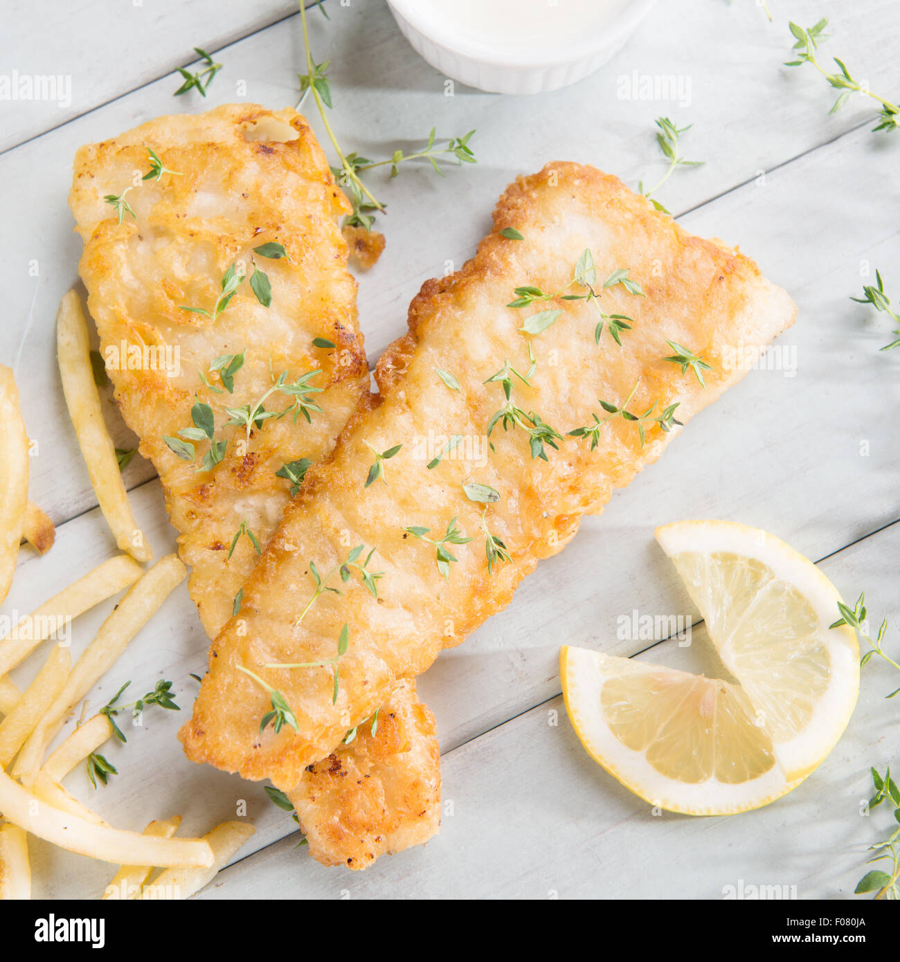 Fish and chips. Above view fried fish fillet with french fries on wooden background. Stock Photo