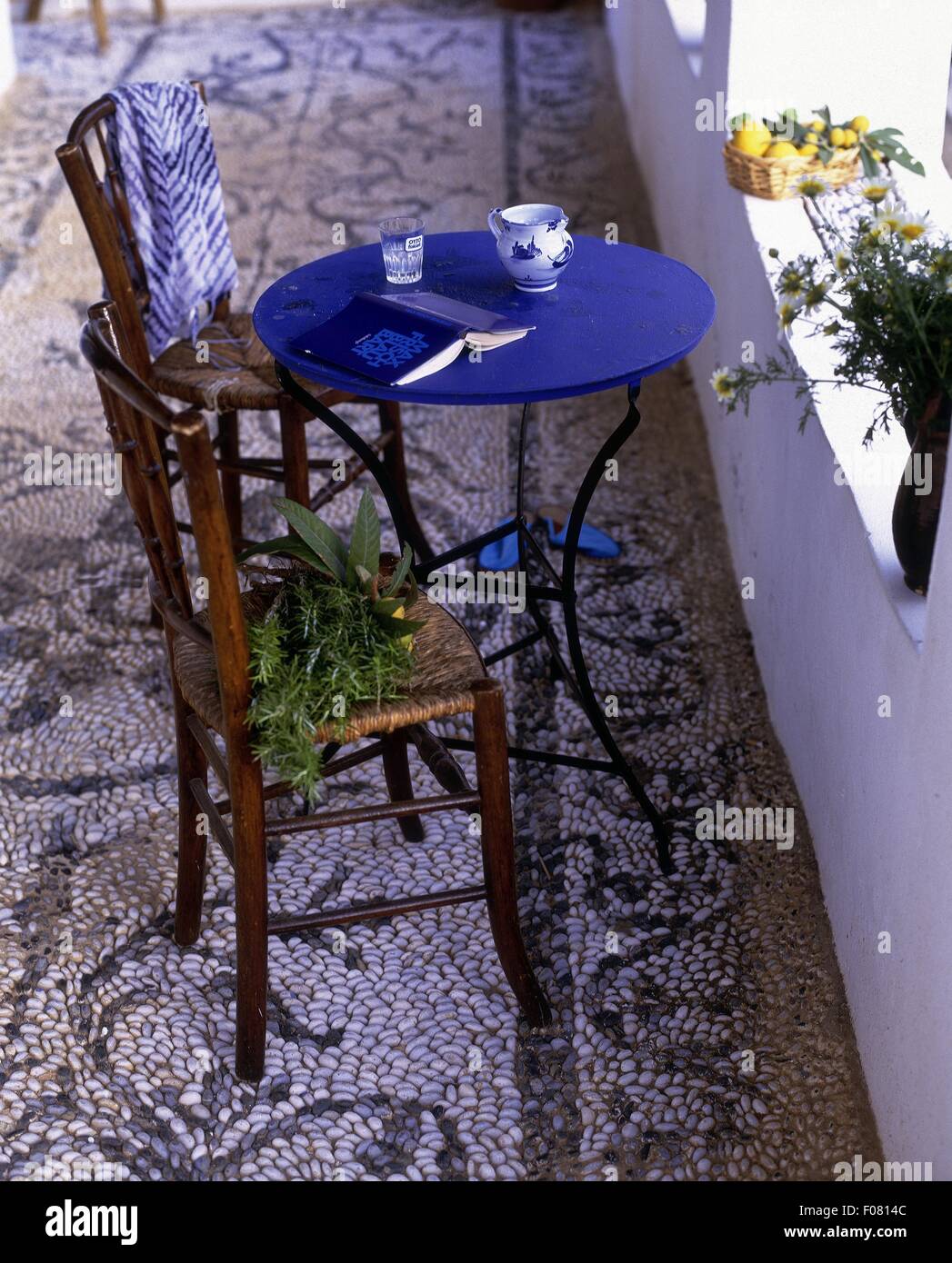 Table and chairs on terrace with ground pebble mosaic Stock Photo