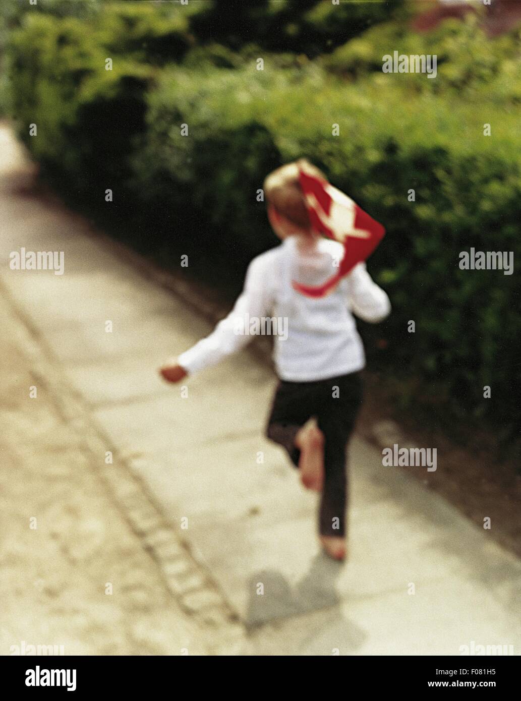 Rear view of little boy running barefoot with Danish national flag, blurred motion Stock Photo
