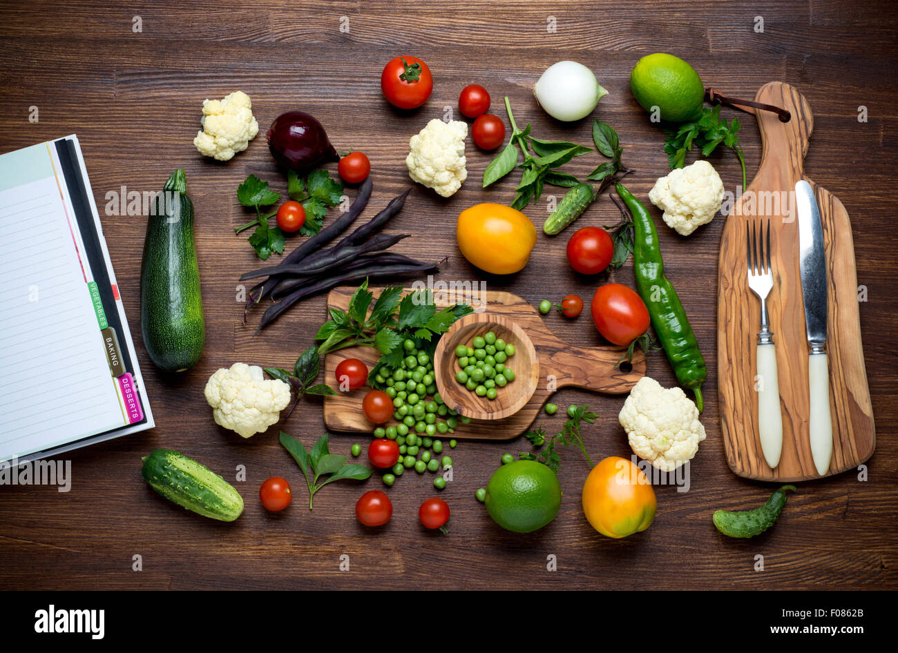 Healthy food. Herbs and vegetables on wooden table with recipe book. Top view. Stock Photo