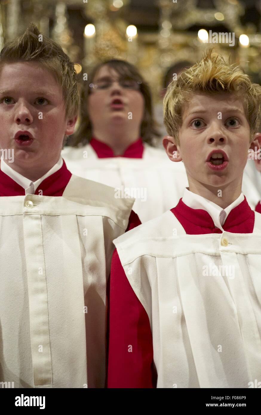 Choir boy's in red and white alter vestments singing in Cathedral Stock