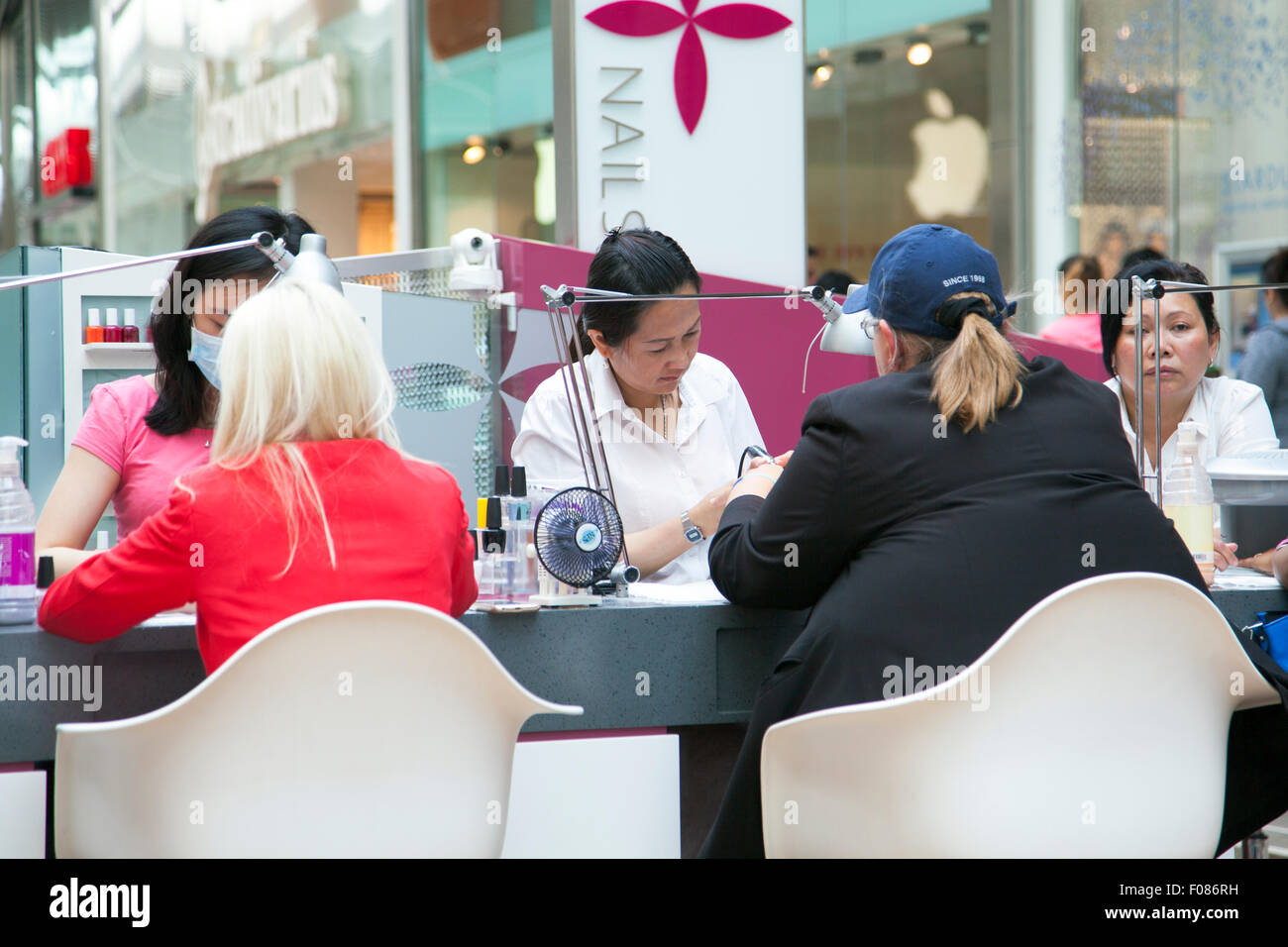 Nail technicians working on clients at a salon Stock Photo