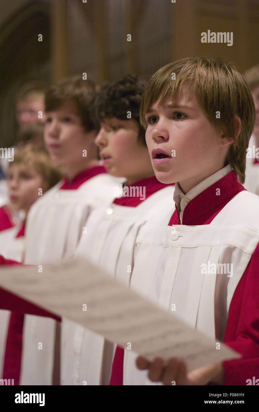 Choir boy's in red and white alter vestments singing in Cathedral Stock