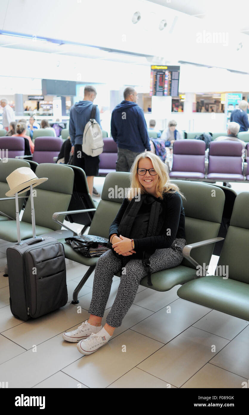 Young teenager girl age 15 looking happy in Departure lounge of Gatwick Airport South Terminal going on holiday Stock Photo