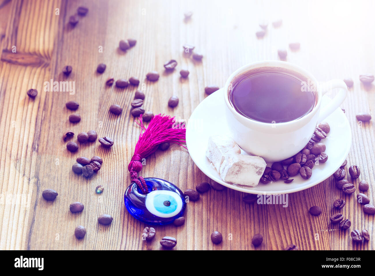 Cup of coffee with Turkish sweets and glass amulet Evil Eye on wooden background Stock Photo