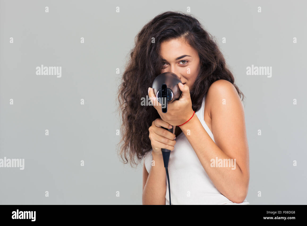 Portrait of a funny woman with hairdryed over gray background Stock Photo