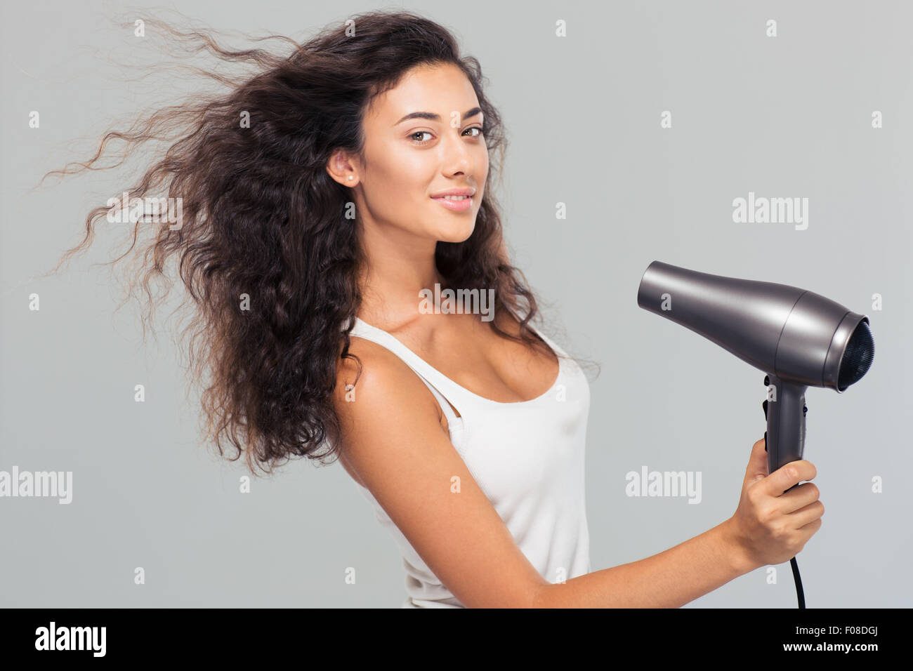 Portrait of a smiling young woman dries her hair over gray background Stock Photo