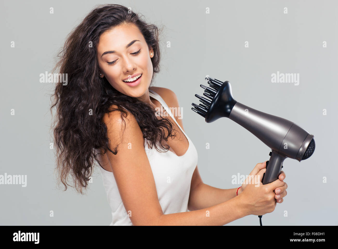 Portrait of a smiling young woman dries her hair over gray background Stock Photo