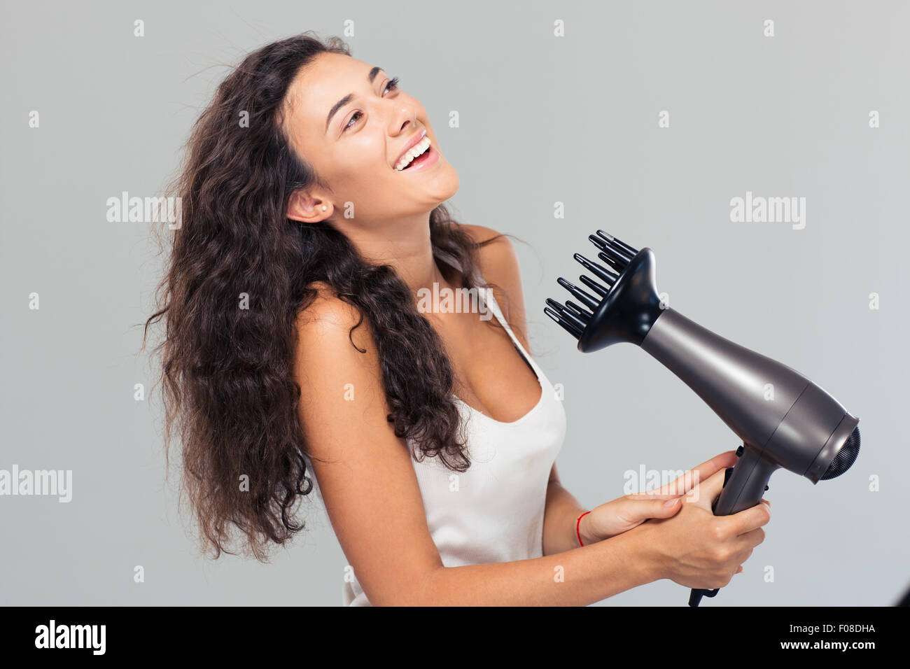 Portrait of a laughing woman dries her hair over gray background Stock Photo