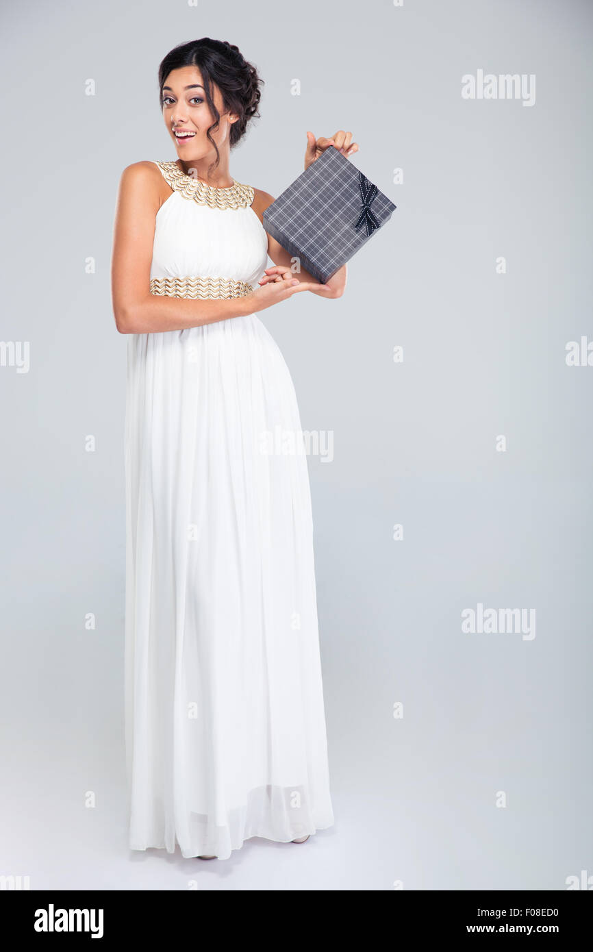 Full length portrait of a beautiful woman in dress holding gift box on ...